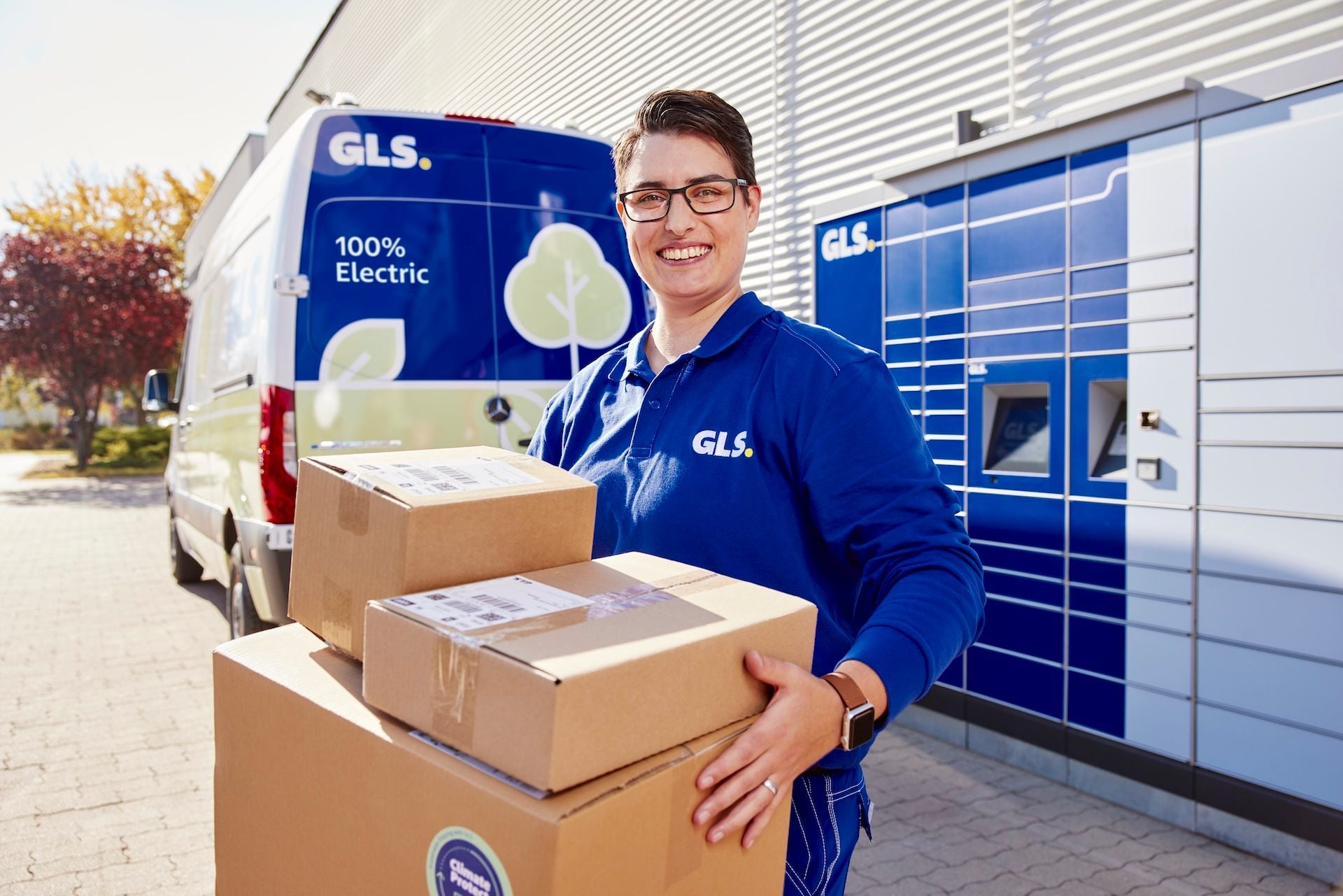 Lieferantin von GLS mit Paketen, im Hintergrund ein E-Transporter
